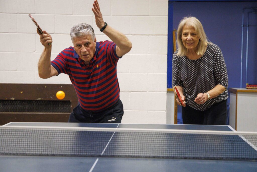 "man and woman playing table tennis"